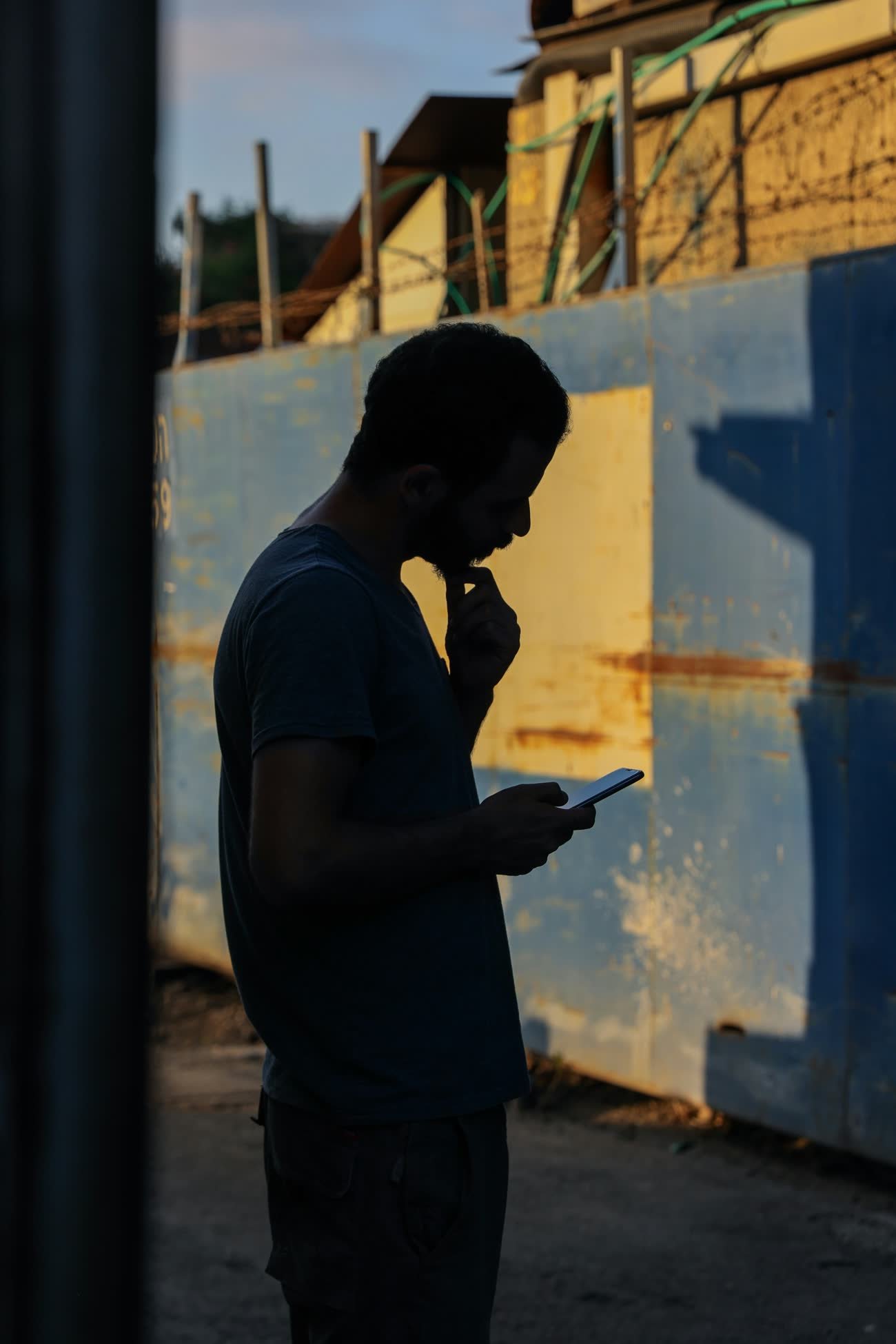 A person checks a phone at dusk, reliant on a network somebody else controls