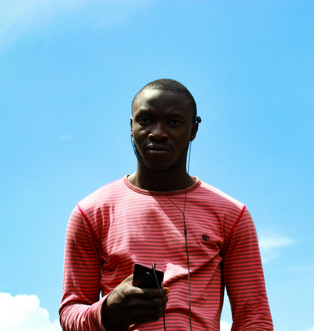 A man stands under open sky holding a mobile phone, connected far from any tower